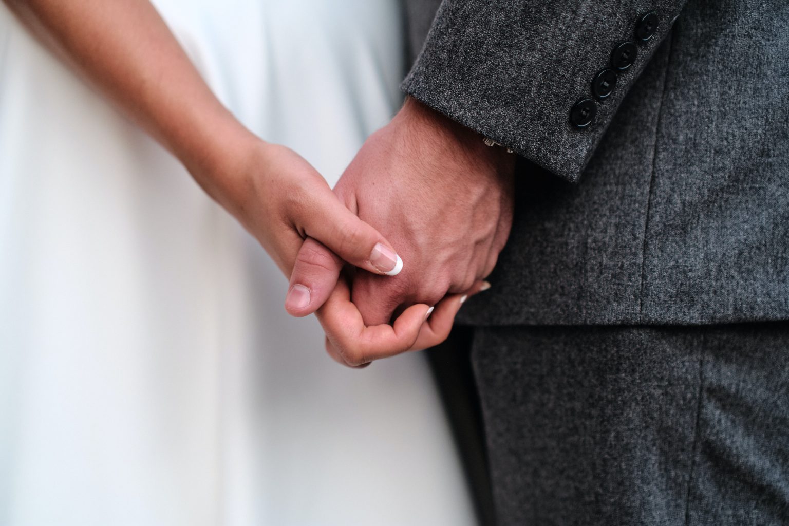 ウェディングドレスとスーツ姿で手をつなぐ新郎新婦